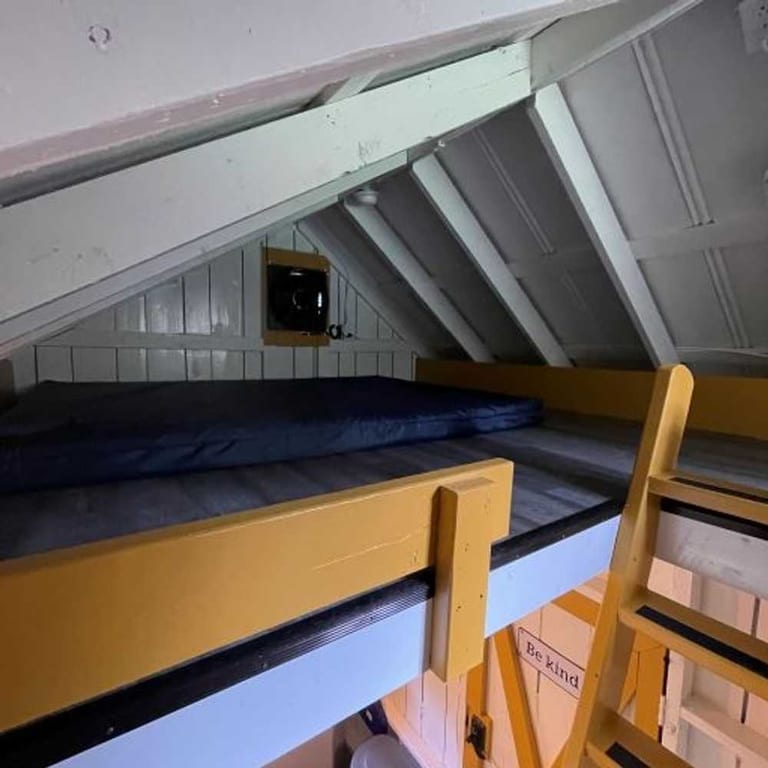 Loft sleeping area with fan in the attached rustic family cabin – Partial Hookup RV with Rustic Family Cabin at The Outpost NRG