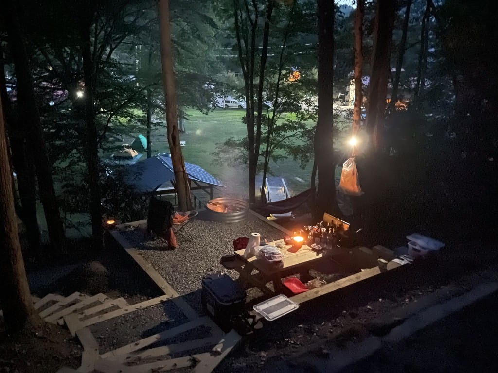 Tent platform at night with fire pit, picnic table, and hammock – Tent Platforms at The Outpost NRG