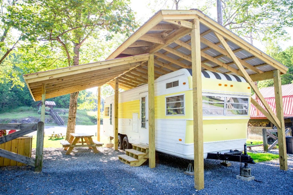 Mellow Yellow vintage camper under a covered wooden pavilion – Mellow Yellow Vintage Camper at The Outpost NRG