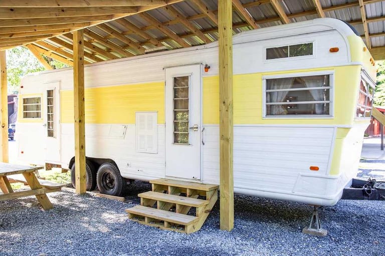 Mellow Yellow vintage camper under a wooden shelter – Mellow Yellow Vintage Camper at The Outpost NRG